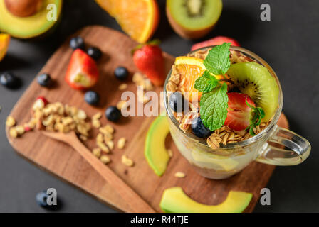 Müsli und Joghurt und Früchte auf Aufstockung in Glas auf Holz Tisch, gesunde Ernährung Konzept Stockfoto