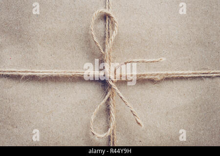 Schnur in einem Bogen auf braun Kraftpapier Textur gebunden. Stockfoto