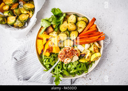 Gebackene Gemüse und hummus Salat in einem weissen Teller, Ansicht von oben. Gesunde vegane Ernährung Konzept. Stockfoto