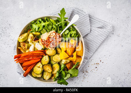 Gebackene Gemüse und hummus Salat in einem weissen Teller, Ansicht von oben. Gesunde vegane Ernährung Konzept. Stockfoto