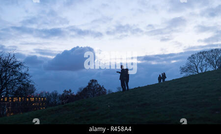 London, Großbritannien. 25. November 2018. UK Wetter - Menschen sind in Silhouette in der Dämmerung im Primrose Hill gesehen. Besucher auf den Gipfel des Hügels sind ein Blick auf die Skyline der Hauptstadt einschließlich der Stadt London, Der Shard und BT Tower. Credit: Stephen Chung/Alamy leben Nachrichten Stockfoto