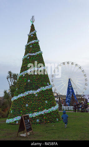 Bournemouth, Dorset, Großbritannien. 25. Nov 2018. Bournemouth Weihnachtsbaum Wunderland mit mehr als 100 glitzernden Bäume und Beleuchtung. Einige der Bäume sind thematisch in sechs Städten rund um die Welt zu repräsentieren - Betlehem Baum im Vordergrund mit St. Petersburg Baum im unteren Gärten und Big Wheel, Riesenrad in der Ferne. Besucher können den Spuren folgen. Stockfoto