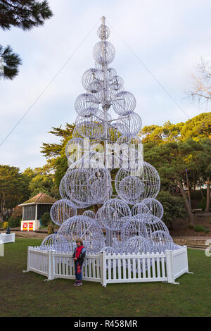 Bournemouth, Dorset, Großbritannien. 25. Nov 2018. Bournemouth Weihnachtsbaum Wunderland mit mehr als 100 glitzernden Bäume und Beleuchtung. Einige der Bäume sind thematisch in sechs Städten rund um die Welt zu repräsentieren - Junge steht vor der Seattle Baum im unteren Gärten. Besucher können den Spuren folgen. Stockfoto