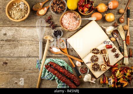 Kochbuch und Gewürz auf einen hölzernen Tisch. Zubereitung von Speisen. Ein altes Buch in der Küche. Rezepte für Lebensmittel. Stockfoto