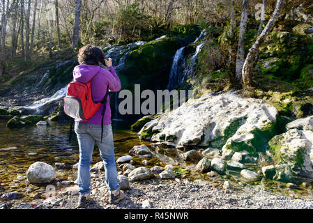 Frau Fotograf fotografieren einen Wasserfall, im Herbst Stockfoto