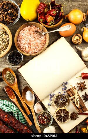 Kochbuch und Gewürz auf einen hölzernen Tisch. Zubereitung von Speisen. Ein altes Buch in der Küche. Rezepte für Lebensmittel. Stockfoto