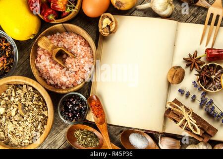 Kochbuch und Gewürz auf einen hölzernen Tisch. Zubereitung von Speisen. Ein altes Buch in der Küche. Rezepte für Lebensmittel. Stockfoto