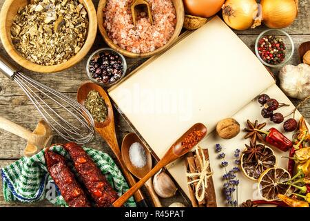 Kochbuch und Gewürz auf einen hölzernen Tisch. Zubereitung von Speisen. Ein altes Buch in der Küche. Rezepte für Lebensmittel. Stockfoto