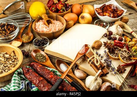 Kochbuch und Gewürz auf einen hölzernen Tisch. Zubereitung von Speisen. Ein altes Buch in der Küche. Rezepte für Lebensmittel. Stockfoto