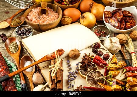 Kochbuch und Gewürz auf einen hölzernen Tisch. Zubereitung von Speisen. Ein altes Buch in der Küche. Rezepte für Lebensmittel. Stockfoto