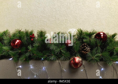 Weihnachtsgirlande in Form von Tannenzweigen mit roten und weißen Weihnachten Spielzeug und Kegel eingerichtet. Stockfoto