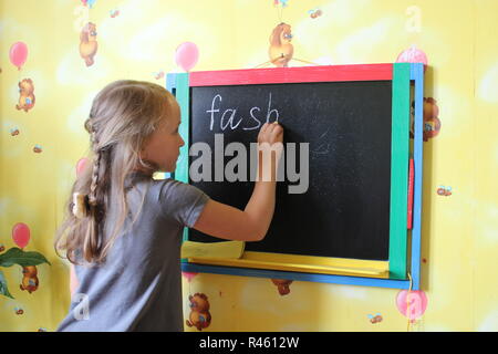 Mädchen mit Zöpfen schreibt Mode auf blackboard Stockfoto