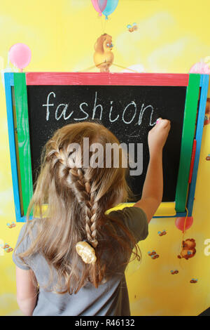 Mädchen mit Zöpfen schreibt Mode auf blackboard Stockfoto