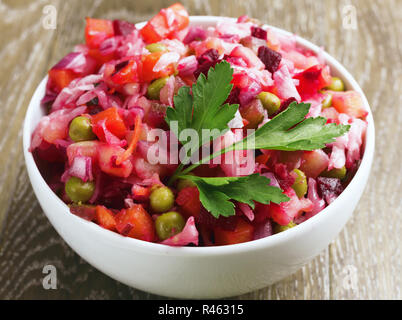 Nahaufnahme. Frische, hausgemachte Rote Beete Salat Vinaigrette in einer weißen Schüssel auf Holz- Hintergrund. Traditionelle russische Küche. Vegetarische Gerichte. Stockfoto