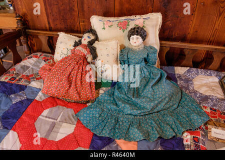 Antike Puppen in den Kleidern auf dem Bett mit handgefertigten Quilts & bestickte Kissen im Schlafzimmer des Hauses in der Chestnut Square Historic Village, McKinney, Texas Stockfoto