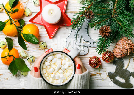 Heiße Schokolade (Kaffee, Kakao) mit Marshmallow in weißen Schale. Weihnachten. Für das neue Jahr. Tannenzweigen, Tangerine, Kerzen, Kegel, Jingle bells und Spielzeug. Holi Stockfoto
