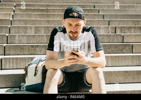 Als Tourist oder Student sitzt auf der Treppe, ruht und verwendet ein Mobiltelefon. Stockfoto