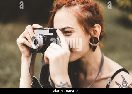 Junges Mädchen mit Tattoos und dreadlocks Fotografien vintage Kamera im Park Stockfoto