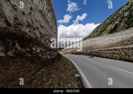 Radfahrer Fahrten zwischen hohen Mauern aus Schnee entlang der Straße nur offen Nufenen Pass in den Schweizer Alpen im Juni Stockfoto