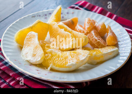 Organic Orange und Mandarine Schichten in der Platte mit roten Tischdecke. Ökologische Lebensmittel. Stockfoto