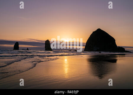 Haystack Rock bei Sonnenuntergang, natürliche Wahrzeichen der Pazifischen Küste, Cannon Beach, Oregon, USA. Stockfoto