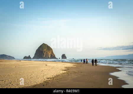 Haystack Rock an einem sonnigen Abend mit Leute am Strand, Cannon Beach, Pazifikküste, Oregon, USA. Stockfoto