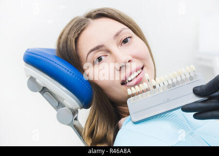 Zahnmedizinische Klinik. Rezeption, die Untersuchung des Patienten. Zähne kümmern. Zahnarzt mit Zahn Farbmuster auswählen Schatten für Frauen Patienten Zähne in der Zahnarztpraxis Stockfoto