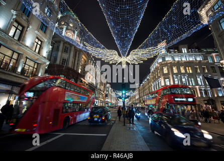 Busy Holiday Shopping Szene mit Doppeldecker Busse und Taxis an fussgänger in einer Winternacht auf der Regent Street, London Stockfoto