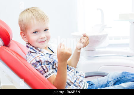 Zahnmedizinische Klinik. Rezeption, die Untersuchung des Patienten. Zähne kümmern. Ein kleiner Junge mit Zahnseide sitzt in einem behandlungsstuhl. Mundhygiene Konzept Stockfoto