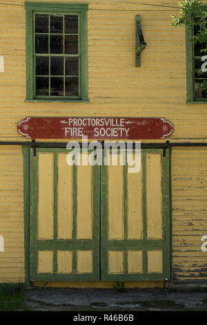 Alte, abgetragene Gelbe und grüne Tür, ehemalige Feuerwache in South Central Vermont. Stockfoto