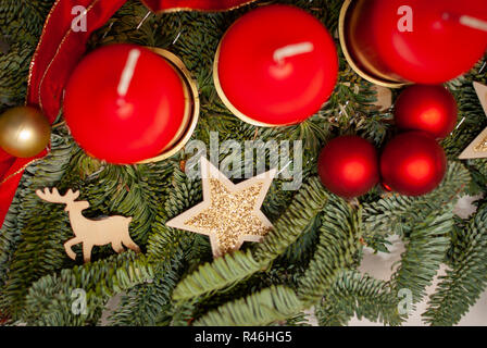 Einen Adventskranz mit vier roten Kerzen auf eine Tanne von Weihnachten Dekoration auf einem weißen Tisch umgeben Stockfoto