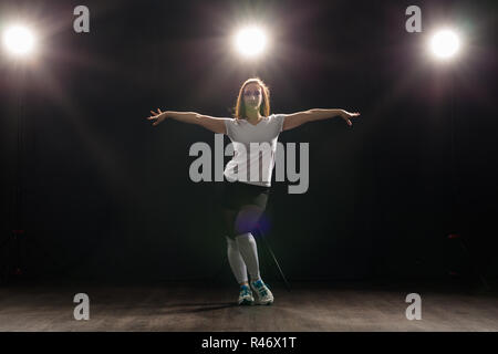 Dance, Hip Hop, Jazz Funk und Personen Konzept - flexible junge Frau tanzen in der Dunkelheit unter dem Licht Stockfoto