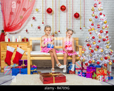 Glückliche Schwester hält Geschenke in ihren Händen, und sitzen auf einer Bank in einem Weihnachts-Ambiente Stockfoto