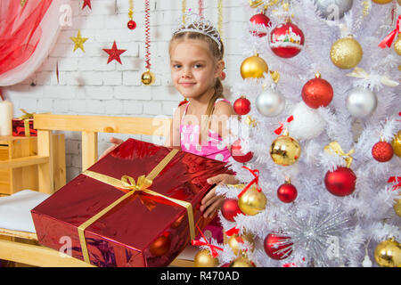 Das Mädchen hält ein riesiges Geschenk aus der Weihnachtsbäume Stockfoto