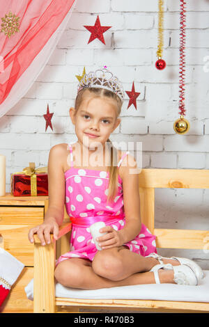 Mädchen sitzen auf einer Bank im Raum Weihnachtsdekoration Stockfoto