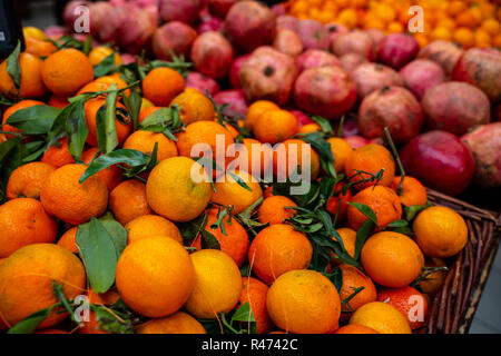 Mangerines und Granatäpfel für Verkauf am Markt in einem Weidenkorb Stockfoto