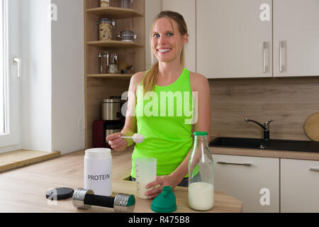 Kaukasische Frau in der Turnhalle Anzug mischen Protein Shake mit Milch Stockfoto