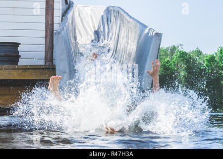 Die Beine und Arme von einer Person auf eine riesige Menge an Wasser spritzen fällt im Sommer am See. Fun Water Entertainment. Stockfoto