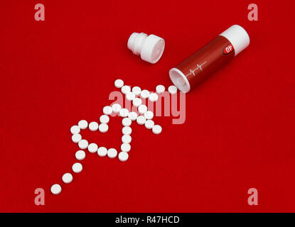 Pillen von Herzkrankheit gegossen aus der Box auf rotem Samt. Die Tabletten in der Form eines Herzens und eines sinusförmigen verstreut. Stockfoto