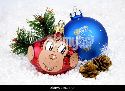 Weihnachtsbaum Spielzeug Affe, ein Ballon mit den Schafen, künstliche Tanne Zweig, zwei Kegel auf dem Hintergrund der künstlichen Schnee. Stockfoto