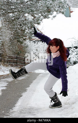 Die Gefahr von Unfällen im Winter - eine Frau rutscht auf rutschiger Fahrbahn Schnee Stockfoto