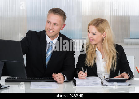 Geschäftsleute mit Schreibarbeit Diskussion über Computer am Schreibtisch Stockfoto
