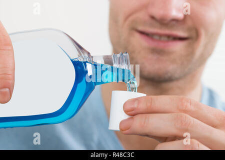 Man gießt Flasche Mundspülung in den Deckel Stockfoto