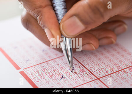 Person Kennzeichnung Nummer auf Lottery Ticket mit Stift Stockfoto