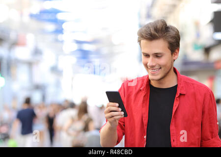 Mann in Rot von SMS auf einem Mobiltelefon Stockfoto