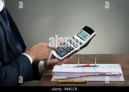 Geschäftsmann mit Taschenrechner bei der Prüfung Rechnung Stockfoto