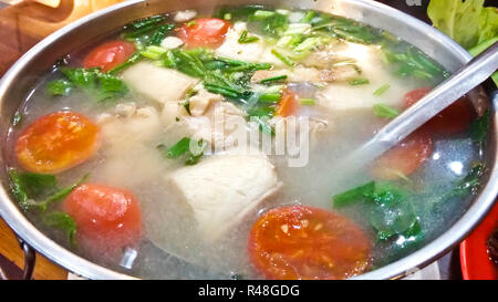 Ausschank von würzigen Fisch Suppe Thai-Stil in einem heißen Topf Stockfoto