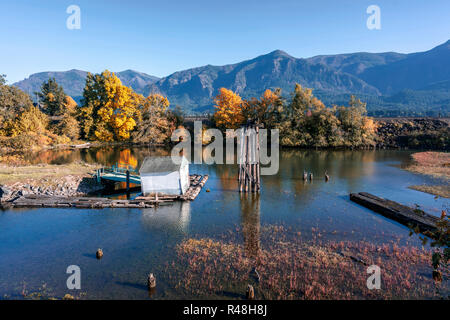 Herbst Landschaft mit einem alten, verlassenen morsches Holz- Pier in der Bucht des Columbia River mit gelben Herbst Bäume am Ufer und Eisenbahn embankmen Stockfoto