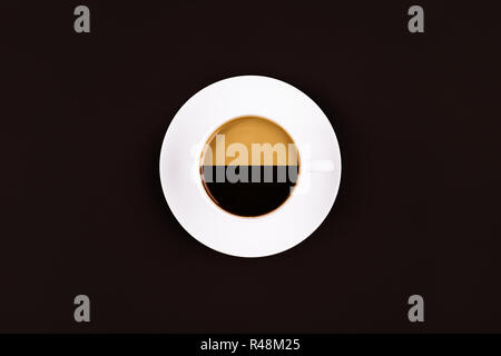 Eine Kaffeetasse mit zwei verschiedenen Arten von Kaffee in es auf dunklem Hintergrund Stockfoto