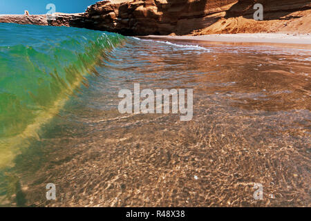 Kleine Wellen brechen am Strand an einem sonnigen Tag Stockfoto